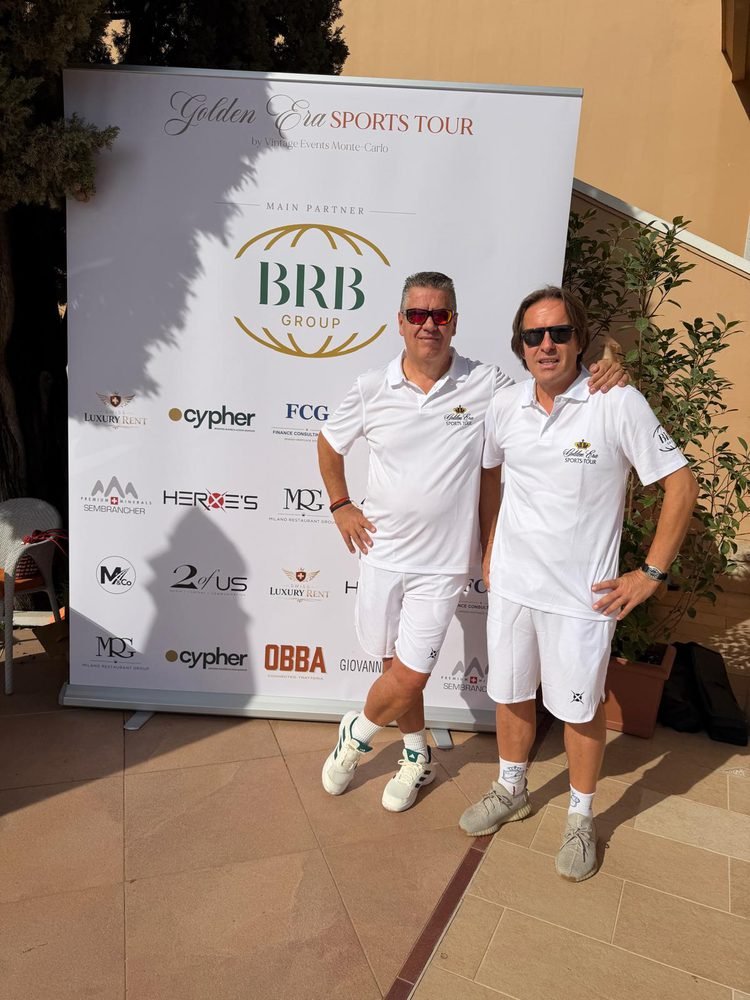 Alberto Bertazzi (left) and another participant in white Golden Era Sports Tour polo shirts in front of the partner wall
